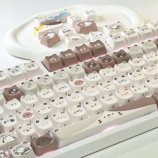 Mocha Cat Keycap Set on a white keyboard with additional keycaps on a tray