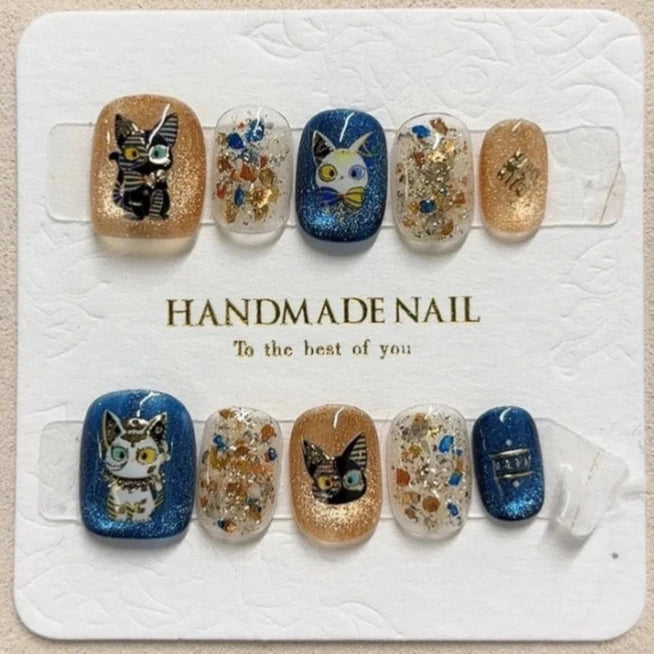 Paws of the Pharaoh handmade press-on nails featuring playful Egyptian cat designs with glitter and gold accents.