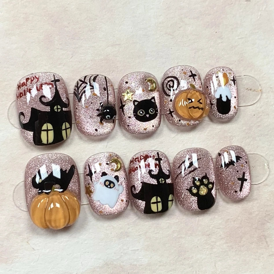Purrfectly Spooky Sparkle handmade press-on nails with pink glittery base featuring black cats, pumpkins, spiders, and cat paw designs. Perfect for Halloween cat lovers.