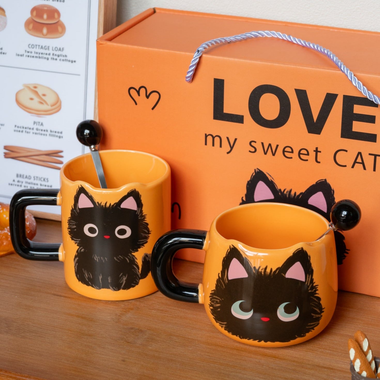 Love My Sweet Cat Coffee Mug, two orange ceramic coffee mug with cute fluffy black cat print, one just with the cute oversized cat head, and another one with the whole body. Mugs with Cute Spoons. Behind is the gift box.