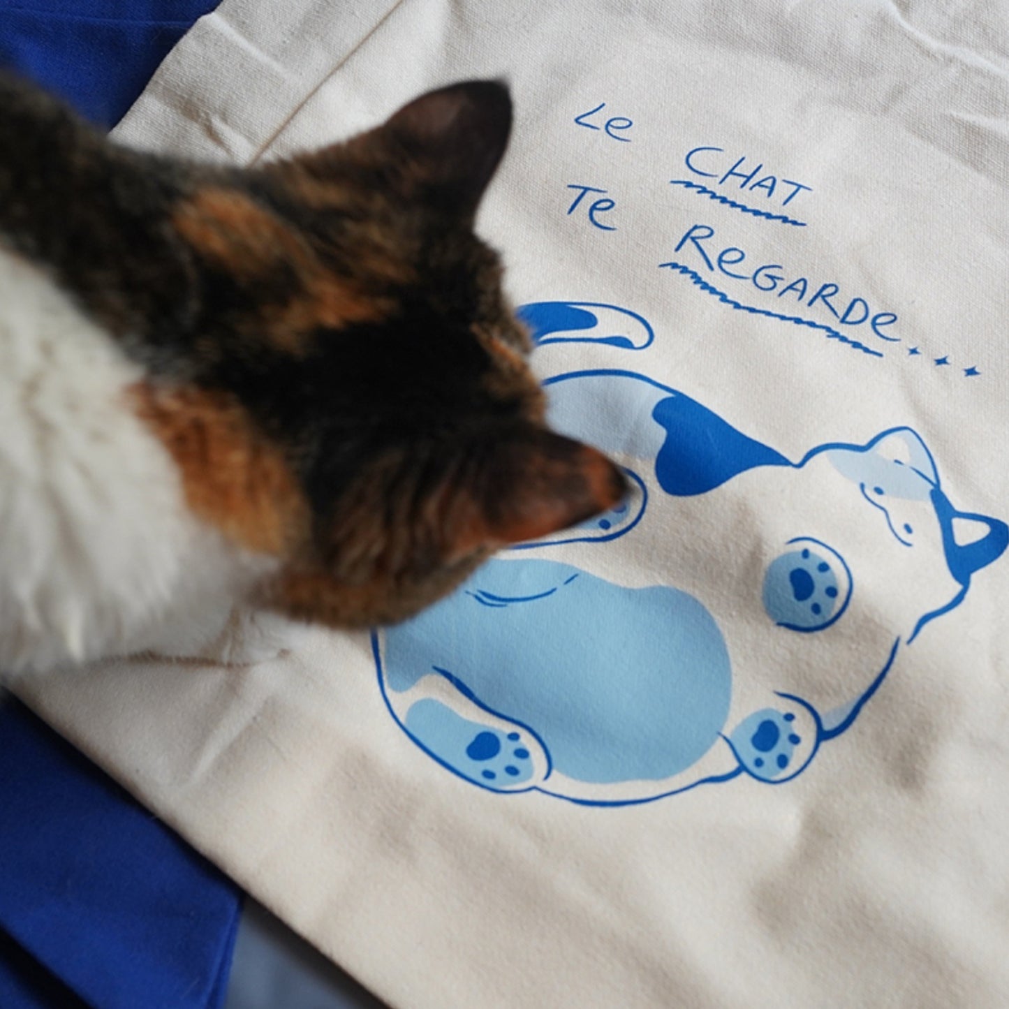 White Cat On Glass Canvas Shopping Tote with the Cute Calico Cat on the table.