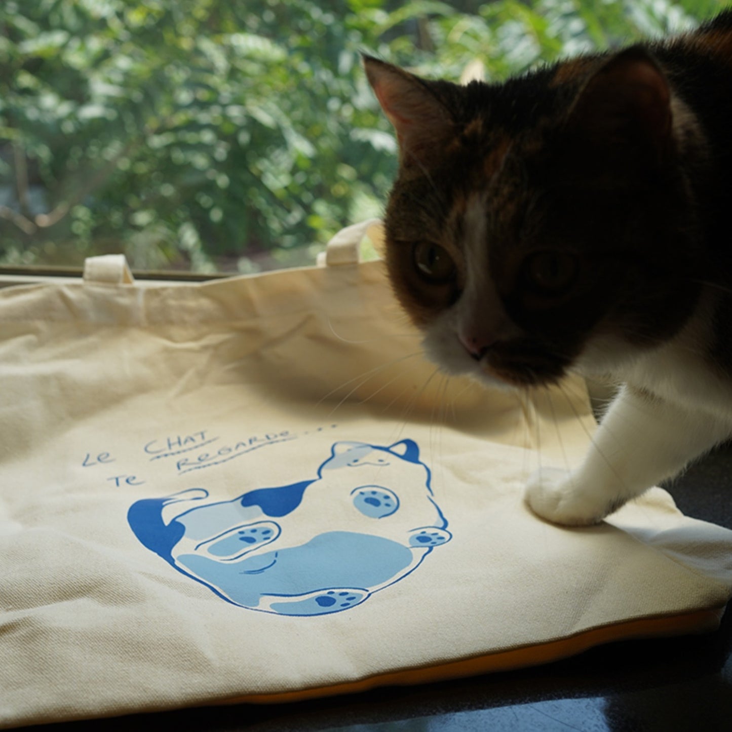 White Cat On Glass Canvas Shopping Tote with the Cute Calico Cat on the table.