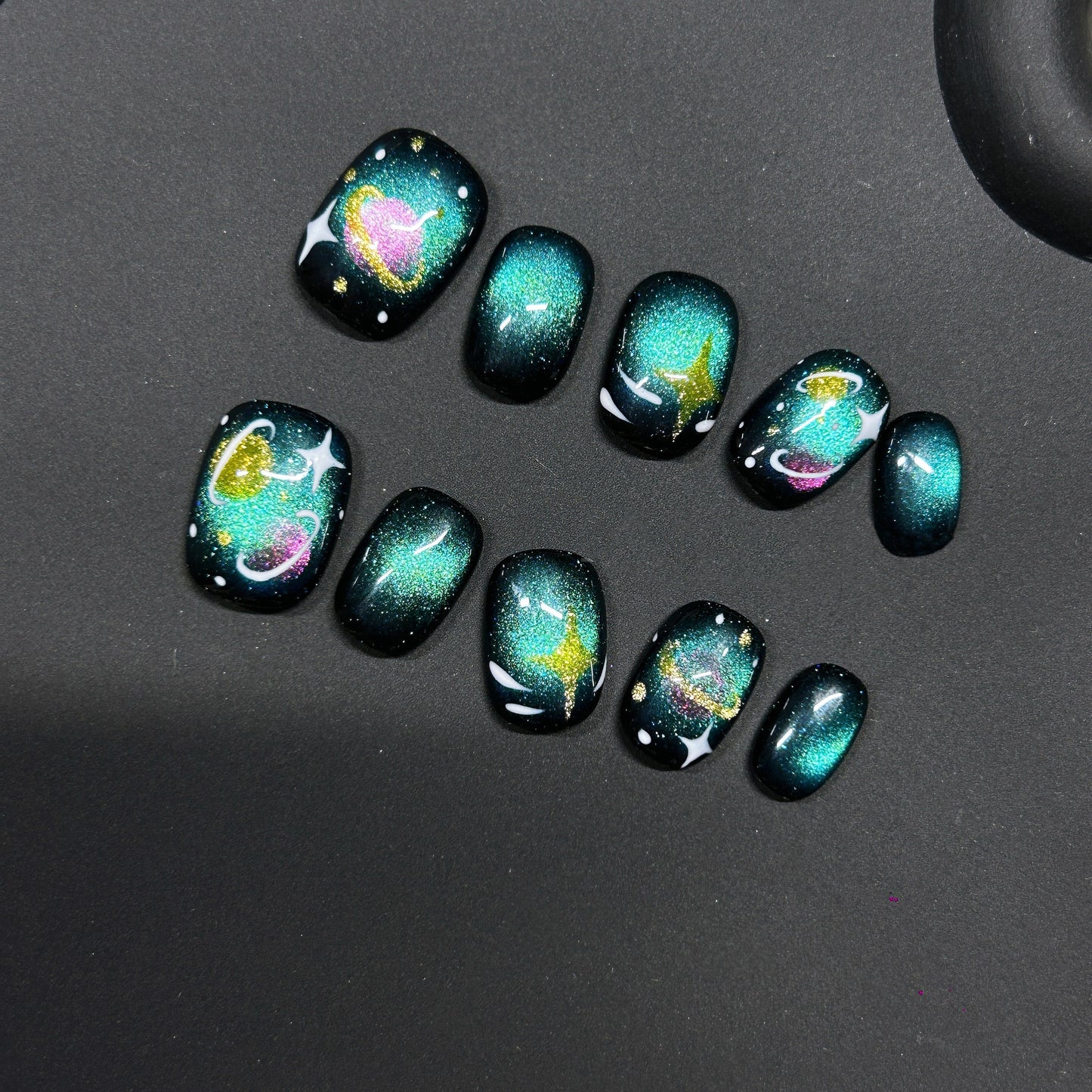 Cosmic Kitty Sparkle cat-eye press-on nails with a glittery space theme featuring hearts, stars, and galaxy swirls.
