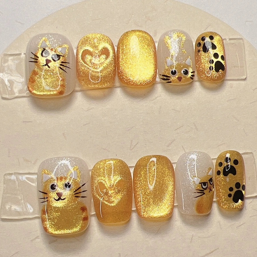 Handmade orange tabby cat nail art with sparkly heart details, perfect gift for cat enthusiasts
