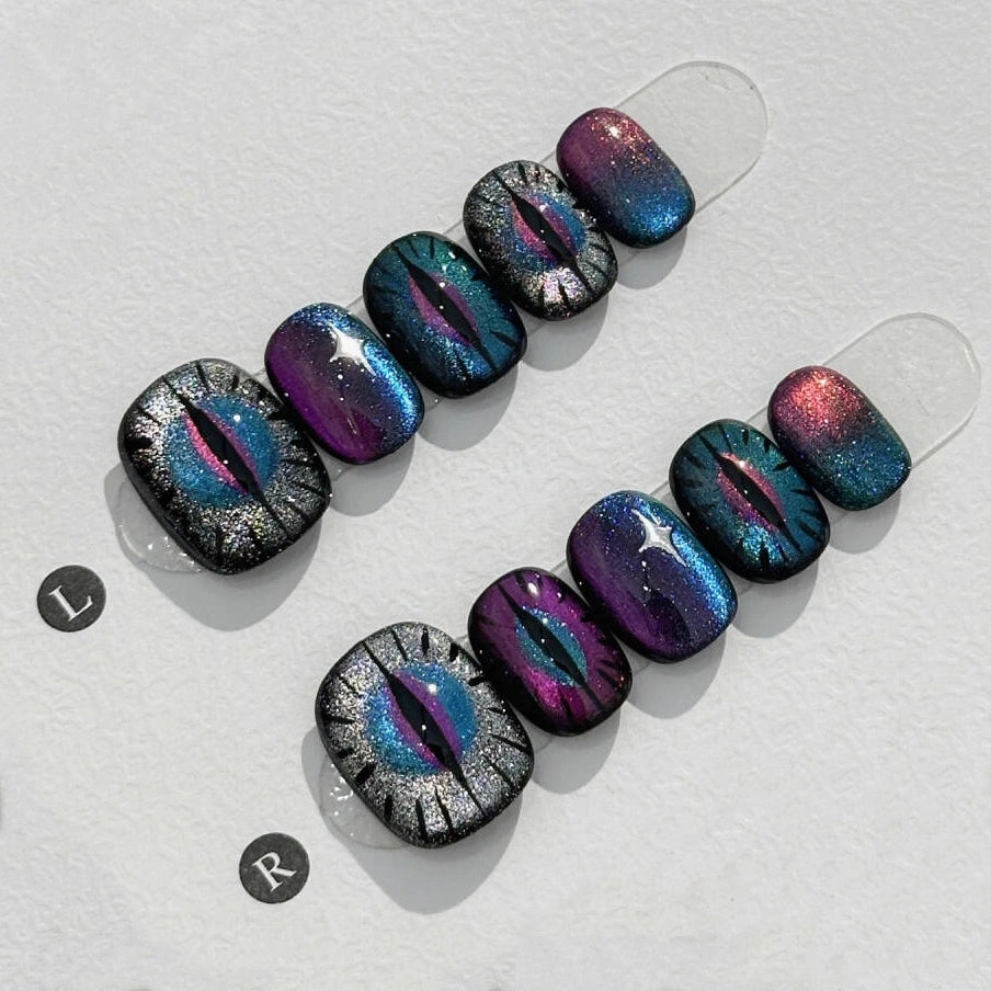 Mystic Meow-gic Eyes Press On Nails featuring cat-eye design, sparkling and holographic in vibrant purples, blues, and black.