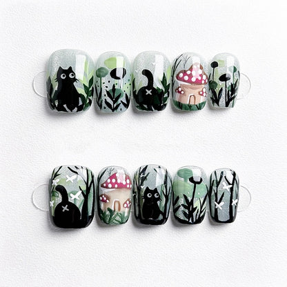 Whiskers in Wonderland handmade press-on nails featuring a playful black cat exploring a whimsical forest with mushrooms and plants.
